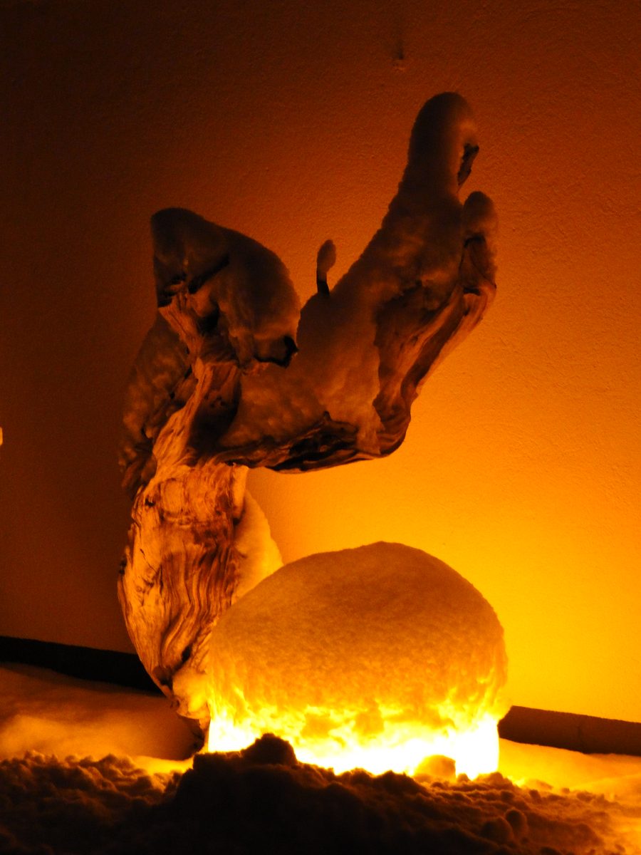 Beleuchtete Wurzelskulptur mit einem leuchtenden Stein davor